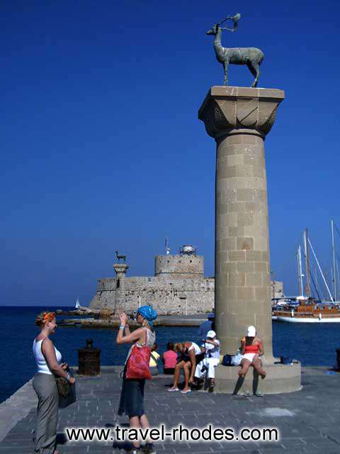 Two girls taking a picture under the deer in the entrance to Rhodes town port  